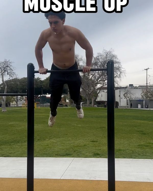 Josh performing a muscle-up on an outdoor bar